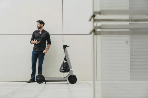 Bo M electric scooter with man standing next to it with bag