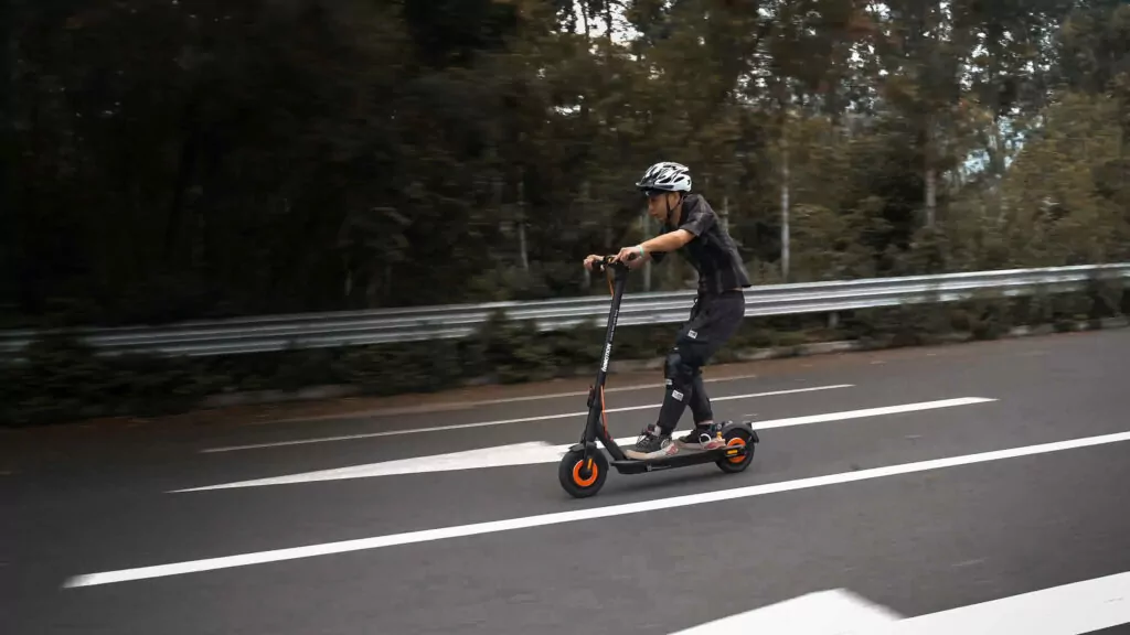 Inmotion Climber Electric Scooter being ridden by a man on a road wearing a helmet showing speed