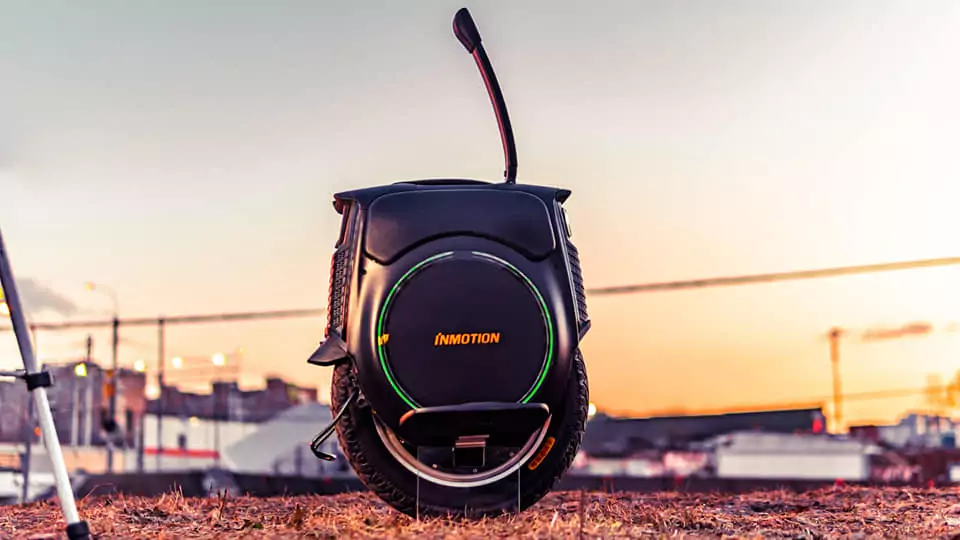 Inmotion V12 Electric Unicycle side view with handle raiised with sunset background